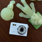 Smiskis toys on a wooden surface with a white camera.