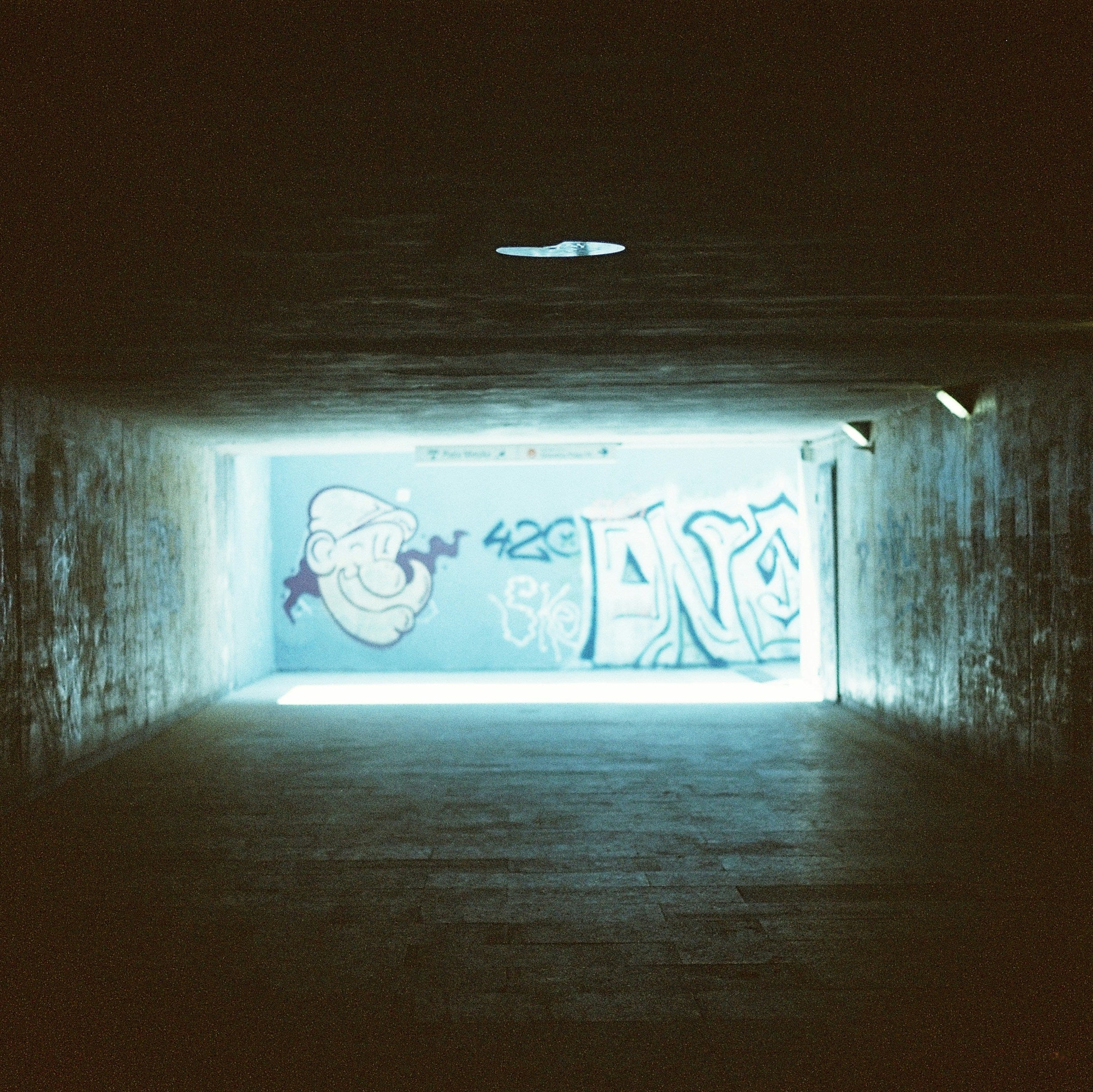 Dark tunnel with graffiti on a wall illuminated by a light source. Shot with SerenoVita VitaCam f(x) Film Camera 