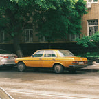Yellow vintage mercedes parked on a street with trees and buildings in the background. Shot with Sereno Vita f(x) Film Camera