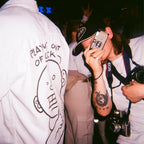 Person taking a photo with a sereno fx camera at a party, wearing a white shirt with text and graphics.