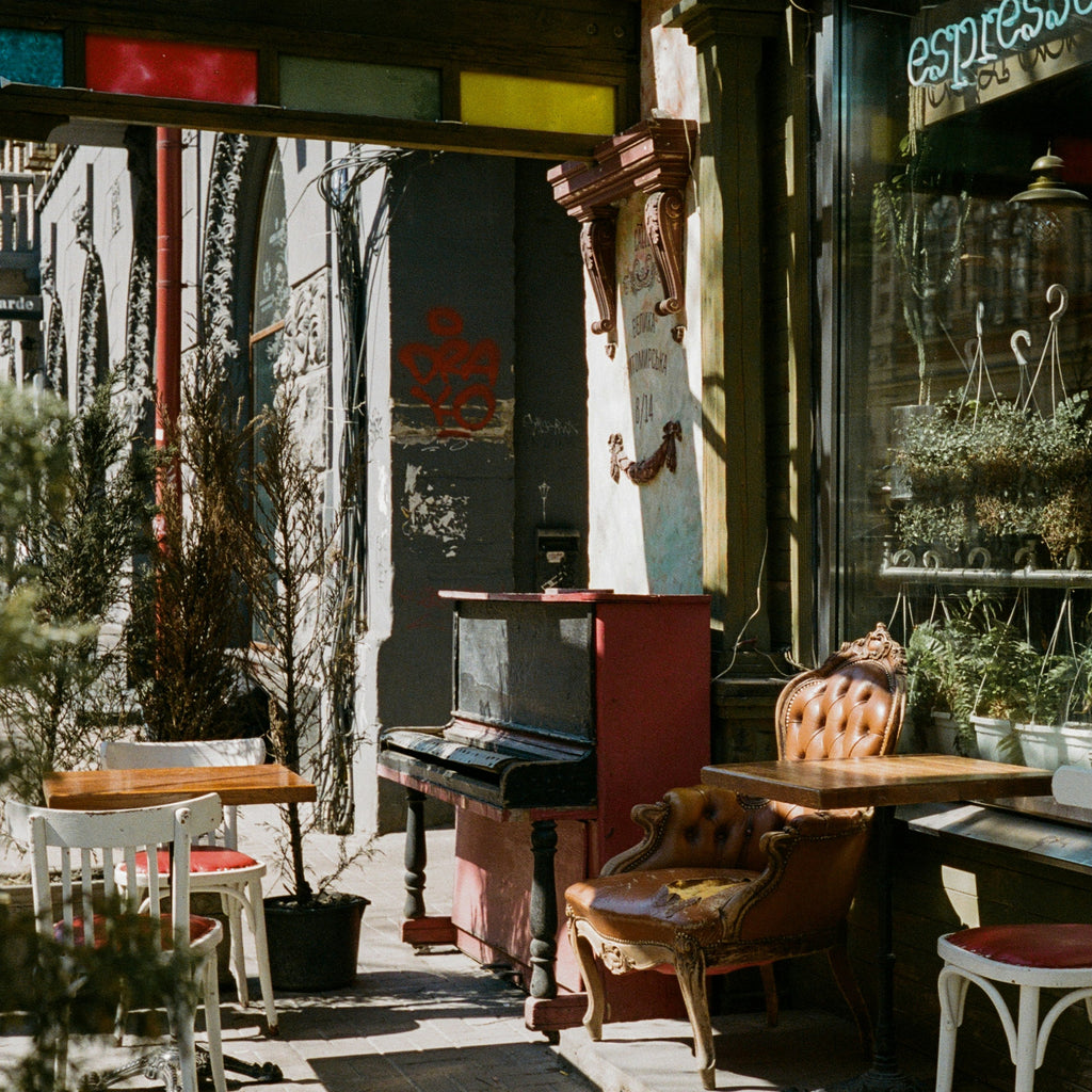 Outdoor seating area of a cafe with tables, chairs, and plants. Shot with SerenoVita VitaCam f(x) Film Camera