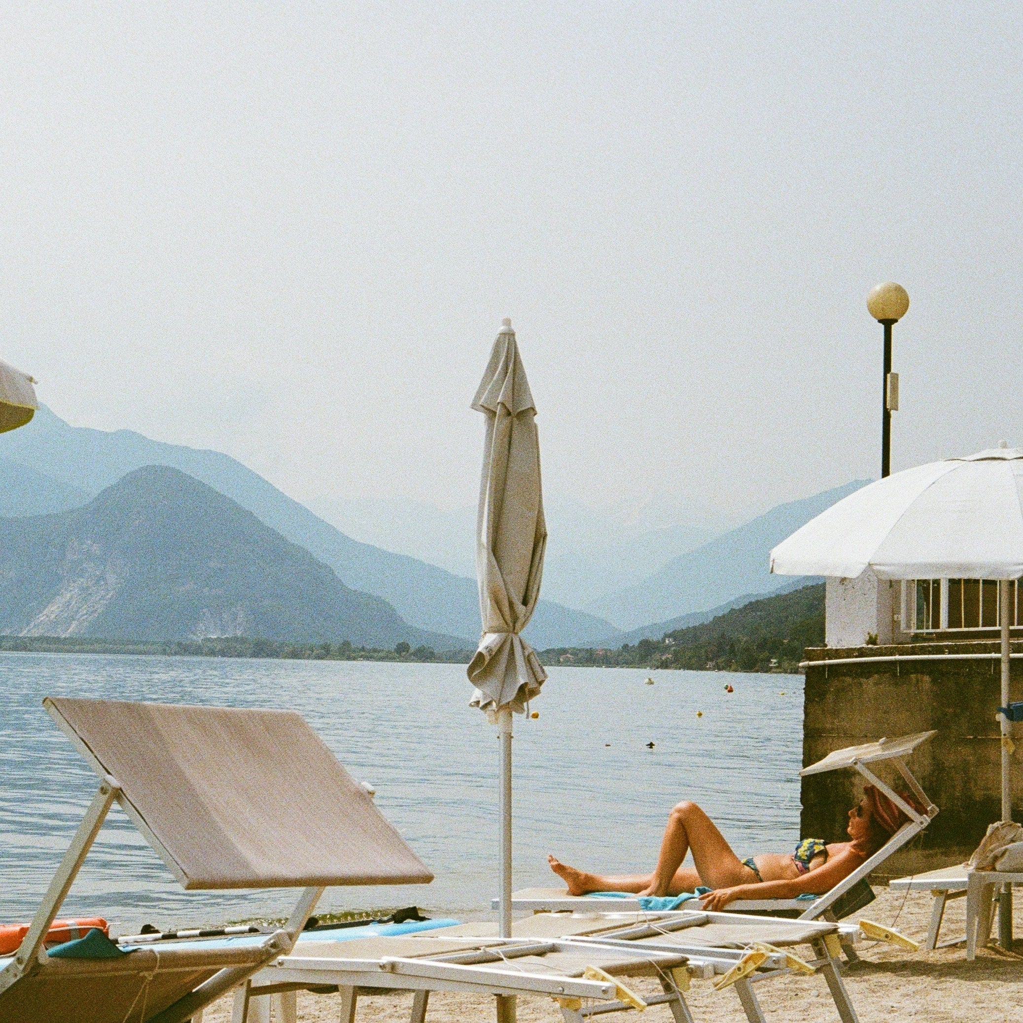 Beach scene with lounge chairs, umbrellas, and a mountain view. Shot with SerenoVita VitaCam f(x) Film Camera 